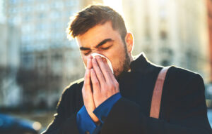Man sneezing from seasonal allergies in need of a natural essential oil remedy