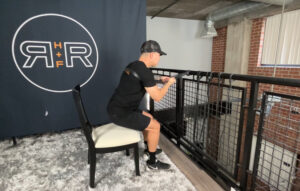 Robert with RR Health + Fitness demonstrating the assisted squat-to-chair exercise with a RR H+F Resistance Band